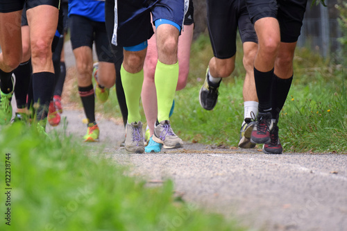 Running competition. Group of men running on a walkway. Closeup of legs.
