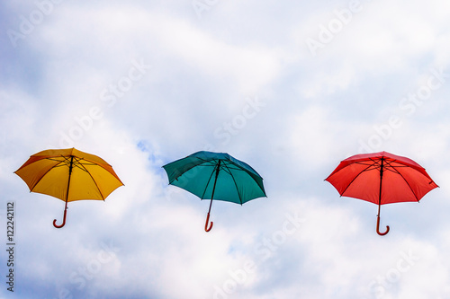 Yellow Umbrella, Green Umbrella and Red Umbrella floating in the Air under Cloudy Sky