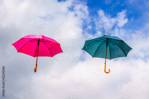 Red Umbrella and Green Umbrella floating in the Air under blue sky and clouds