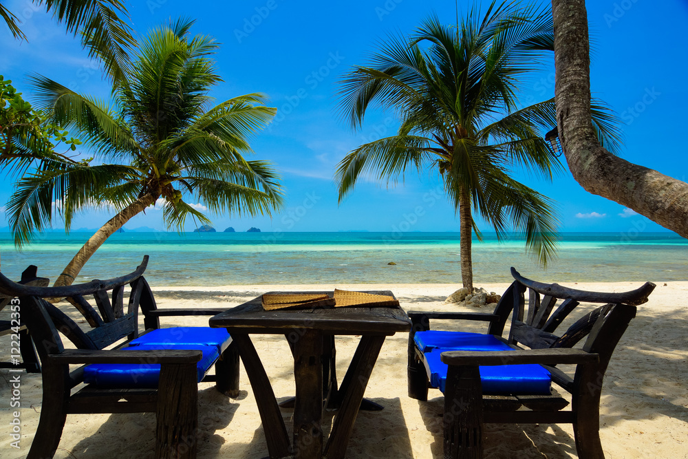 Bänke mit Tisch am Strand unter Palmen