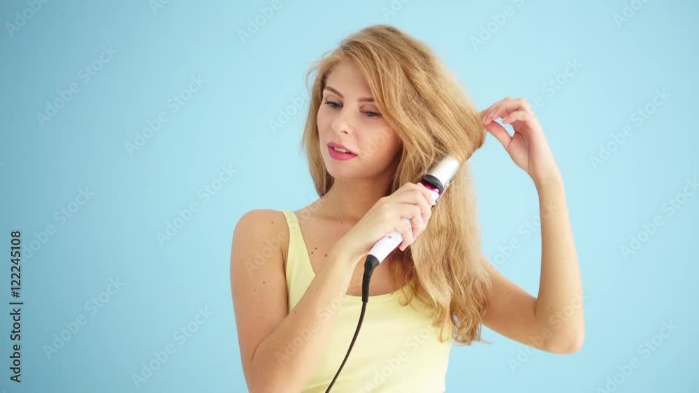 Beautiful woman curling her hair