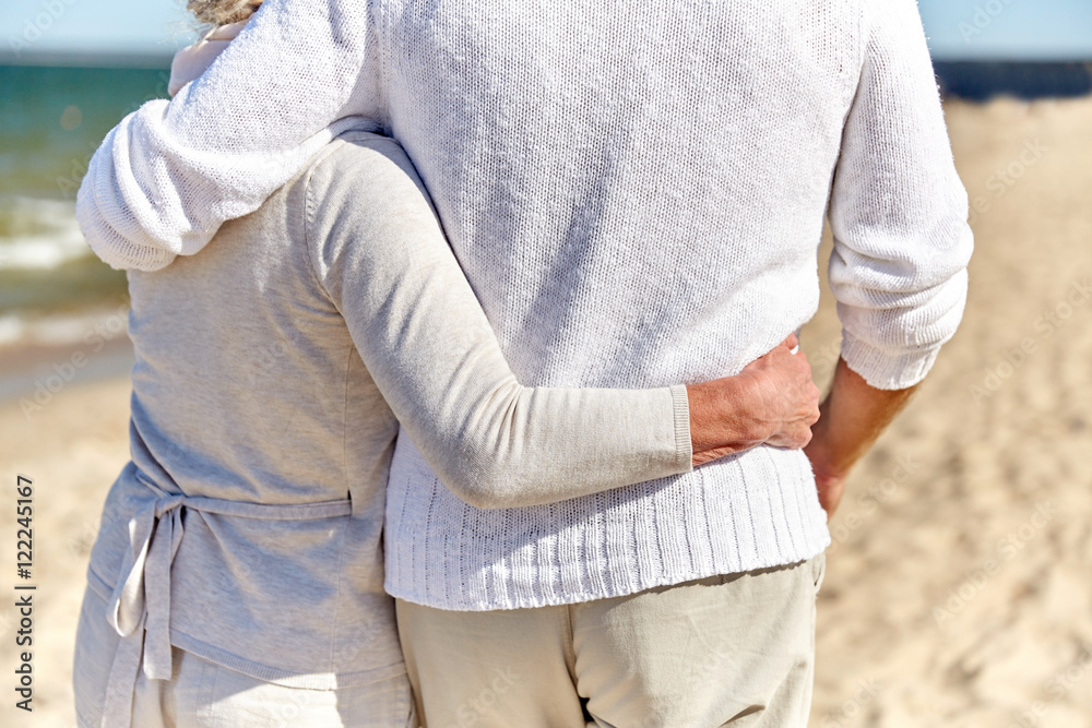 close up of happy senior couple hugging on beach