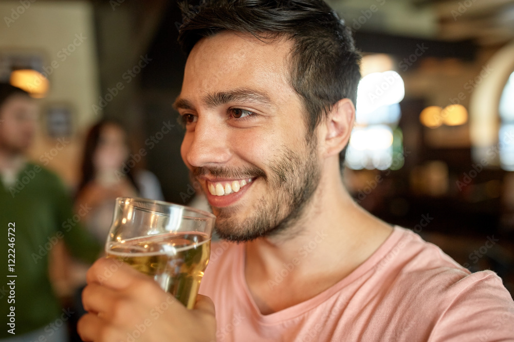 close up of happy man drinking beer at bar or pub