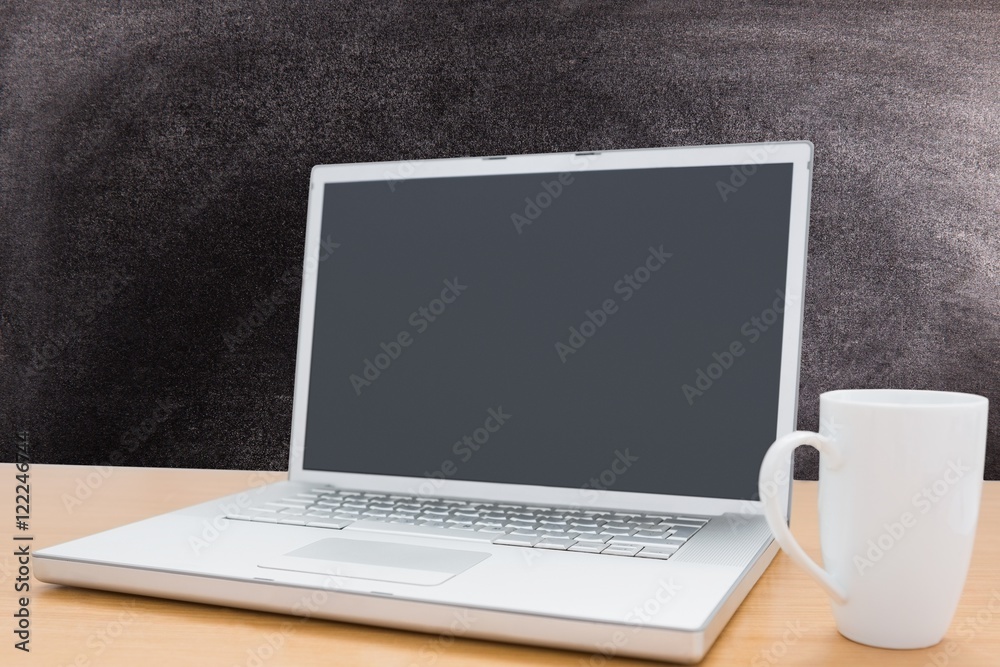 Fototapeta premium laptop with coffee mug on chalkboard background