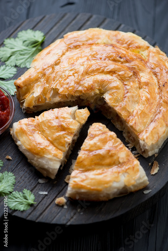 Close-up of sliced burek pie with meat stuffing, selective focus