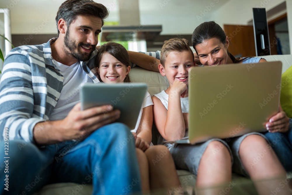 Happy family using laptop and digital tablet in the living room Happy family using laptop and digital tablet in the living room