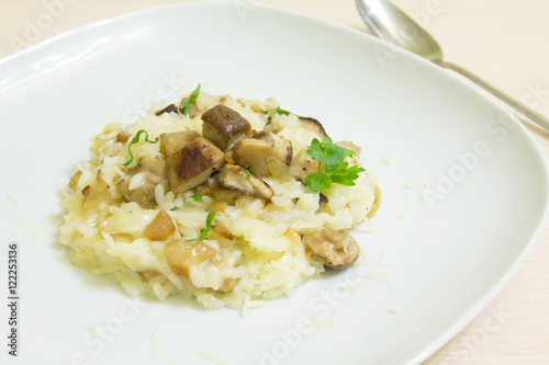 Risotto with mushrooms, parmesan cheese and parsley on a wooden background