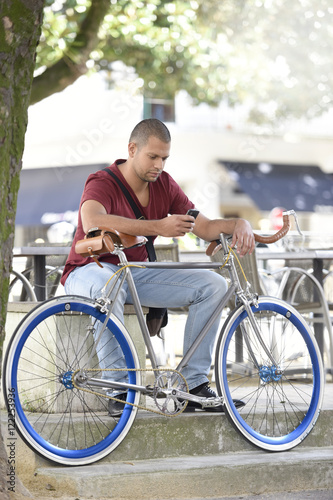 Man with bicycle sitting on park bench © goodluz