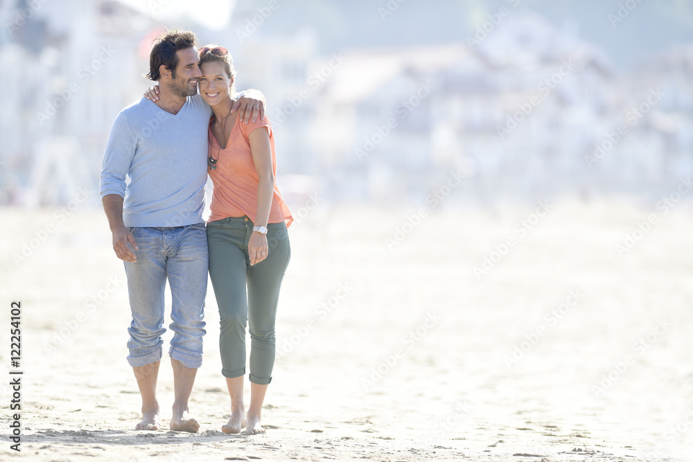 Middle-aged couple walking on the beach - obrazy, fototapety, plakaty 