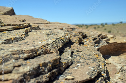 Close up of lichen covered layered stone overlooking desert landscape 