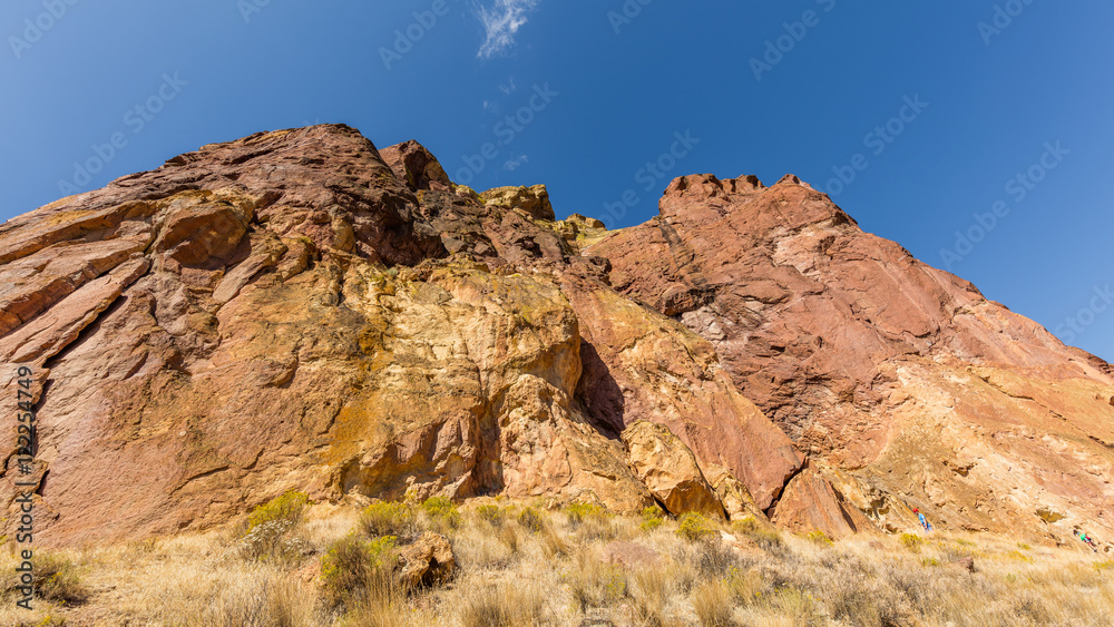 The sheer rock walls. Beautiful landscape of yellow sharp cliffs. Dry yellow grass grows on the slopes of the mountains. Smith Rock state park, Oregon