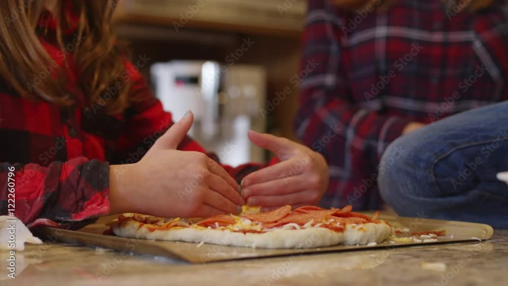 Siblings making homemade pizza together in the kitchen, putting toppings on Siblings making homemade pizza together in the kitchen, putting toppings on