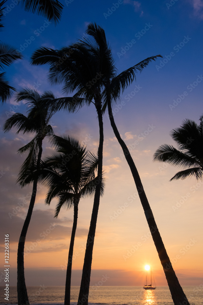 A sailboat at anchor at sunset along the coast of Kailua-Kona, Hawaii on the Big Island.