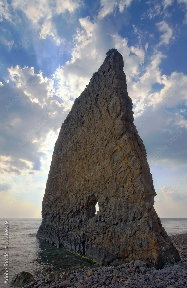 Naklejka premium Sail-like rocky tooth jutting out into the sea