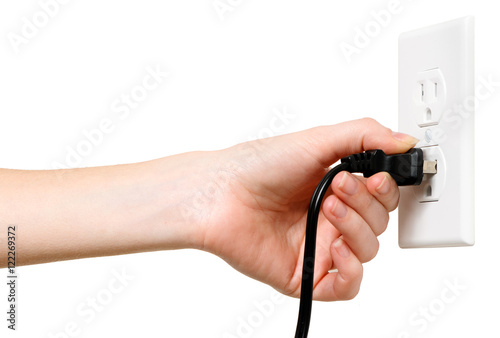 Woman's hand plugging unplugging U.S. electrical cord into outlet isolated on white background for use alone or as a design element
