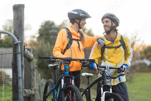 Biker couple interacting while standing with mountain bike