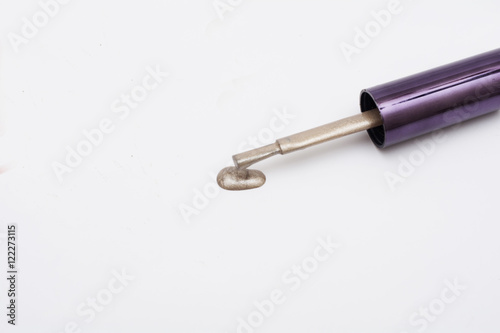 Close up of a nail polish bottle and drop on white background