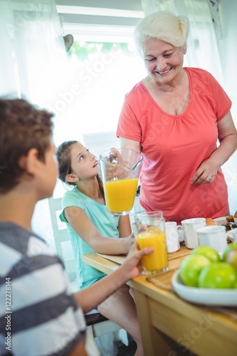 Grandmother pouring orange juice in glass