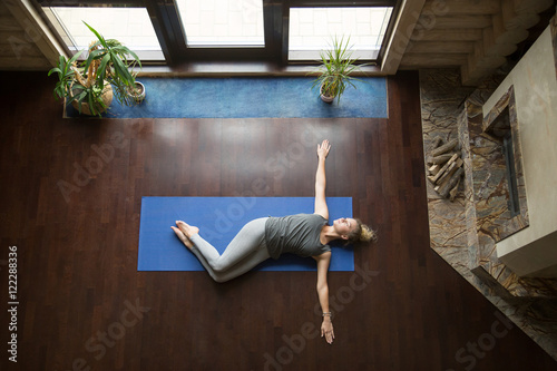 Fotótapéta Attractive young woman working out in living room, doing yoga exercise on wooden