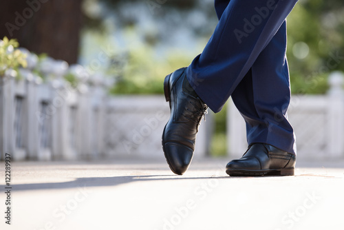 Man's feet in blue trousers and blue shoes
