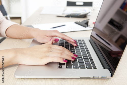 Woman hand typing on laptop keyboard