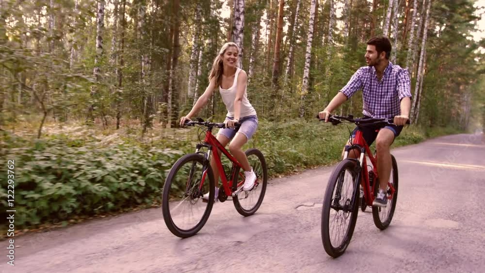Portrait of happy couple having fun on bicycle ride in the summer park Portrait of happy couple having fun on bicycle ride in the summer park