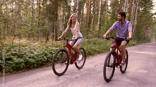 Portrait of happy couple having fun on bicycle ride in the summer park