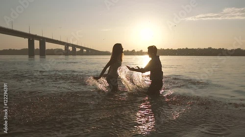 Playful couple spraying with water in the river