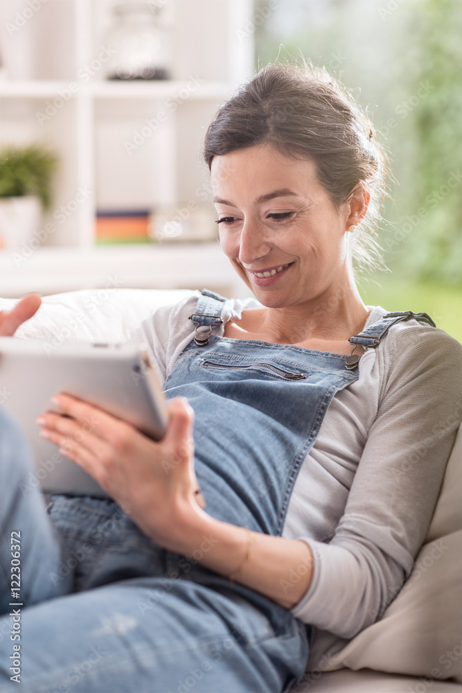 Obraz premium young pregnant woman at home using a tablet