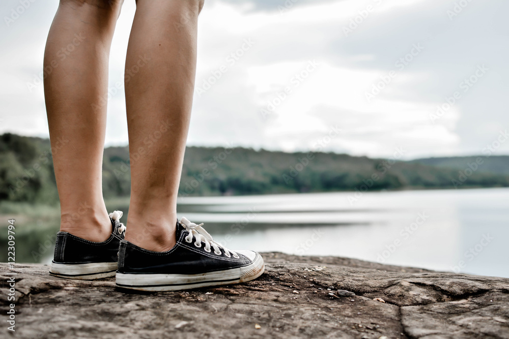 Feet women black sneakers on nature. Selective focus and Hipster tone Feet women black sneakers on nature. Selective focus and Hipster tone