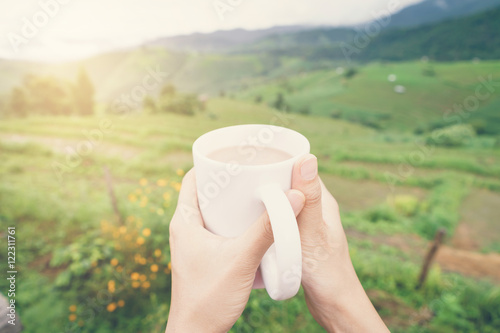 Woman holding a cup of coffee with beautiful landscape