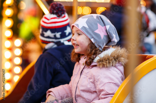 little boy and girl, siblings on carousel at Christmas market