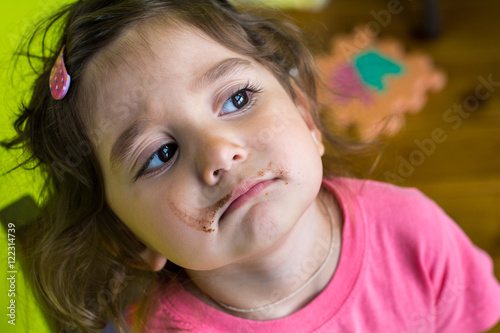 Portrait of a child - a girl. She smiles. Her face was smeared with a strip of chocolate.