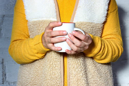 Woman holds a hot cup of tea and warms his hands