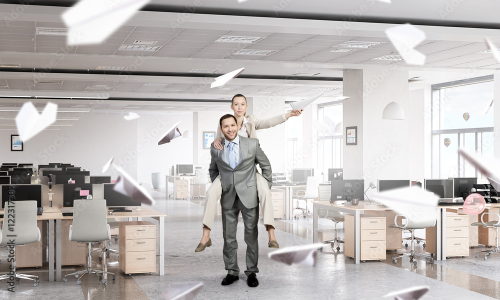 Businesswoman riding colleague back . Mixed media Businesswoman riding colleague back . Mixed media