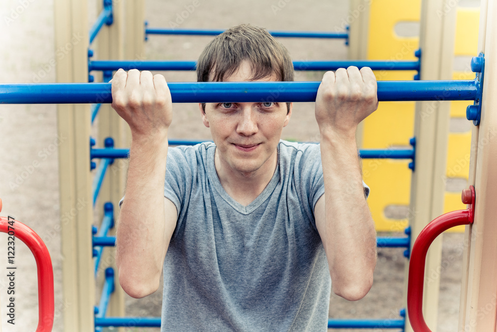 Naklejka premium Man doing physical exercises - pulling. Hanging on the bar. 