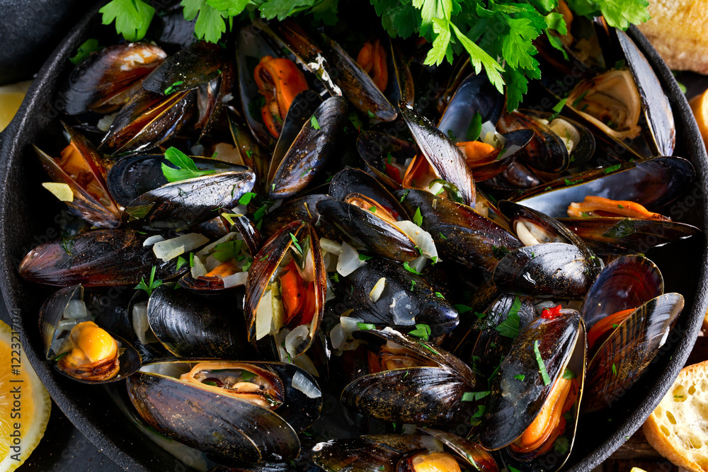 Boiled mussels in iron pan cooking dish. with herbs, butter, lime, parsley, garlic and fresh bread. Boiled mussels in iron pan cooking dish. with herbs, butter, lime, parsley, garlic and fresh bread.