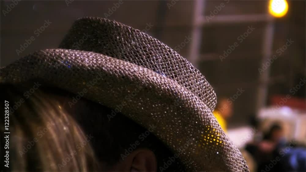 A spectator at an event at night wearing a straw cowboy hat. HD 1080.