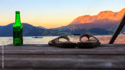 Steg mit Flip Flops, Getränk mit Bergpanorama