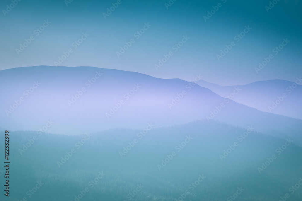 Landscape with colorful layers of mountains and haze in the valleys. The effect of color tinting.