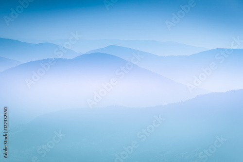 Landscape with colorful layers of mountains and haze in the valleys. The effect of color tinting.