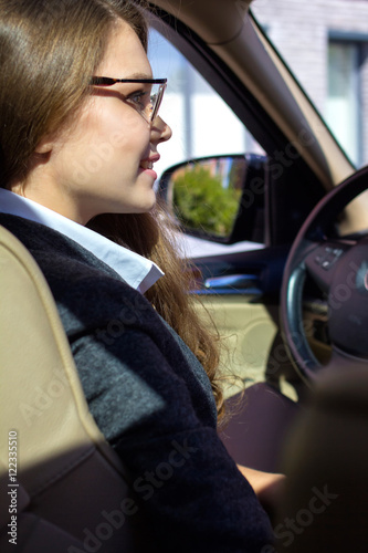 молодая женщина в очках сидит за рулем автомобиля