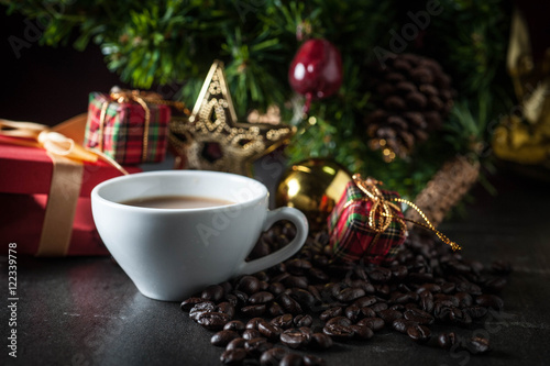 Coffee cup and christmas toys with pine brench on black stone background.