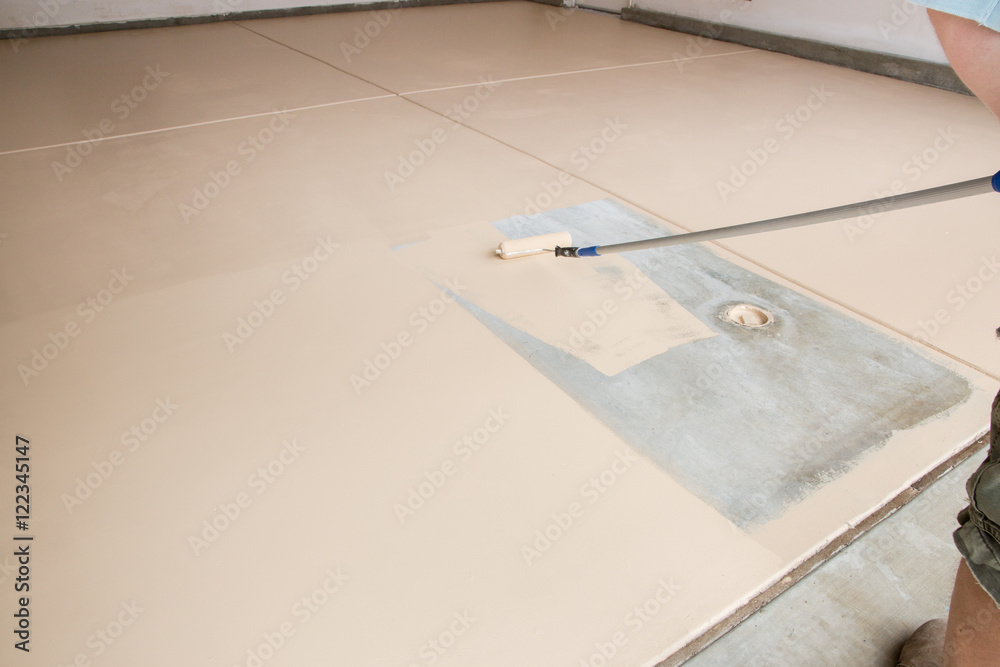 Worker Painting Floor of Garage with Roller. Worker Painting Floor of Garage with Roller.