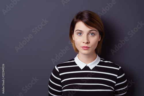 selbstbewusste junge frau vor grauer wand im studio