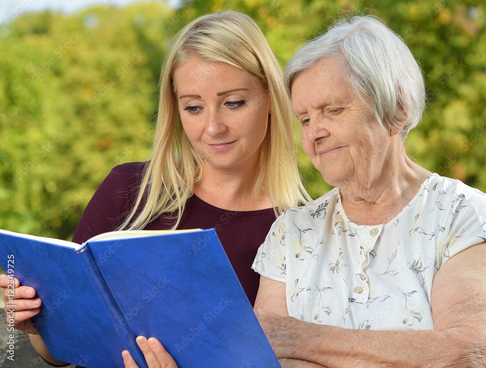 Young woman reading a book elderly woman in the park.