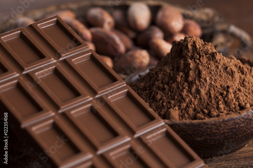 Chocolate bar, candy sweet, cacao beans and powder on wooden bac