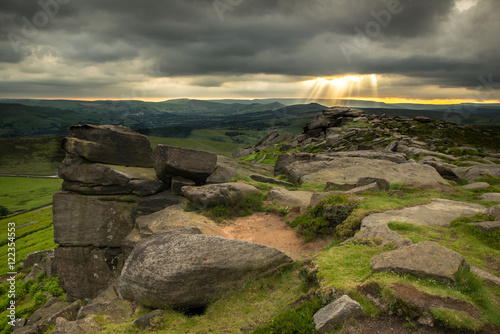 Sun rays breaking through clouds over Stanage Edge