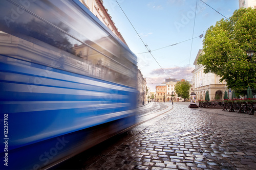 Photography Blue tram rides on the morning  old european city.