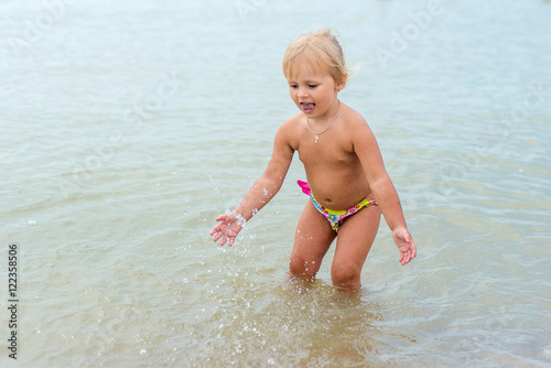 Adorable toddler girl playing with beach toys on white sand beach